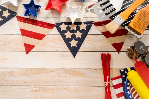 American flag decorations sit on a table next to ketchup, mustard, plates, and napkins.