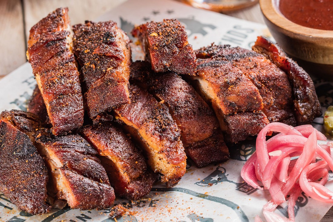 A huge piece of Famous Dave's Texas Beef Brisket, sliced, with a side of pickled onions