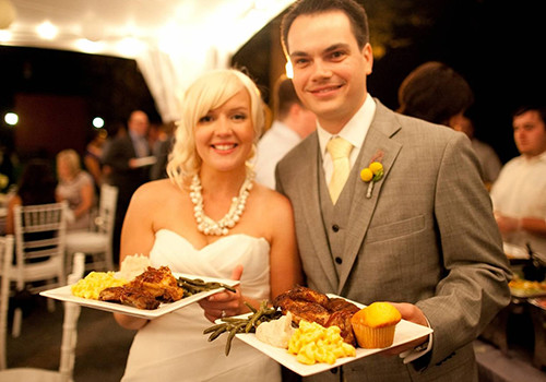 A newly married couple at their wedding holding plates of Famous Dave's BBQ