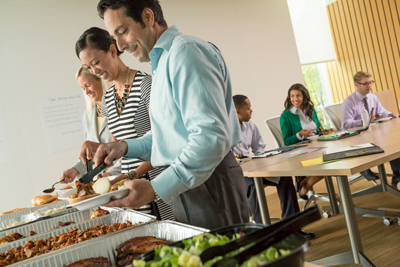 People standing in line and grabbing food at a corporate catering buffet