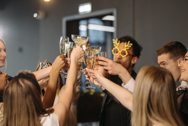 A group of coworkers cling glasses at a company holiday party. 